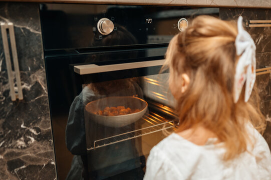 Little Caucasian Girl Watching Oven With Pie, Golden Crust Visible Through Glass, Warm Oven Glow, Curious