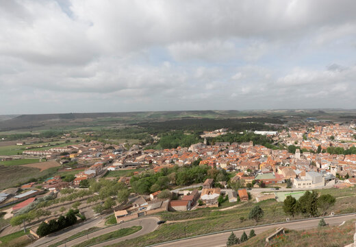 Aerial view of Pe&ntilde;afiel, Spain, featuring its dense urban landscape with terracotta roofs, historic church towers, and modern architecture integrated into the traditional Castilian town center.