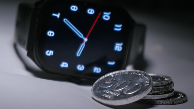 Digital smartwatch with Indonesian rupiah coins representing time and financial management