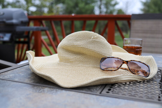 A big floppy straw hat and sunglasses on a patio table