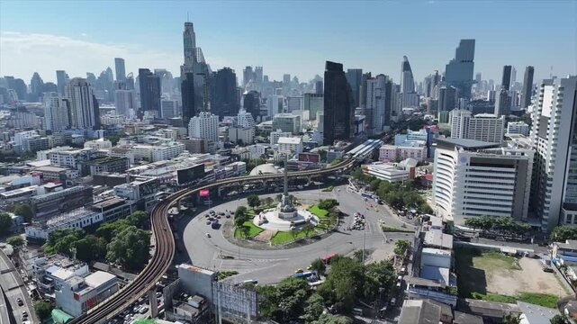 Vehicles forming circular motion patterns around Victory Monument with dynamic traffic flow in the city center.