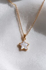 Fototapeta premium Star Pendant Necklace: A delicate and stylish gold chain necklace, featuring a charming star-shaped pendant adorned with iridescent, mother-of-pearl, resting on a soft, textured fabric.