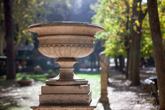 Close-up of a decorative stone urn under bright sunlight in the gardens of Villa Borghese.