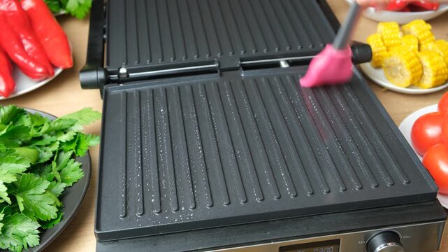 Greasing Electric Grill Plate with Pink Silicone Brush for Cooking