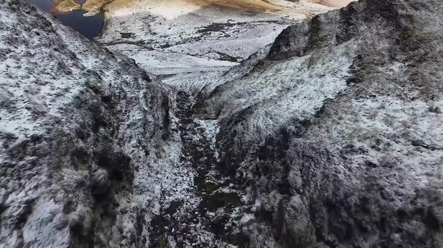 FPV Drone Shot Plunging Dow a Steep Snowy Volcanic Rok Cliff and Gorge