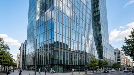 Obraz premium A modern glass skyscraper with a reflective facade, standing tall against a clear blue sky with scattered clouds.