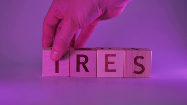 A hand moves wooden blocks to spell different words, starting with 'stress' and transitioning to 'rest'. The background is bright with purple lighting, creating a focus on the wordplay