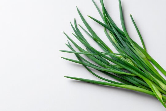 Vibrant green garlic chives arranged on a clean white surface