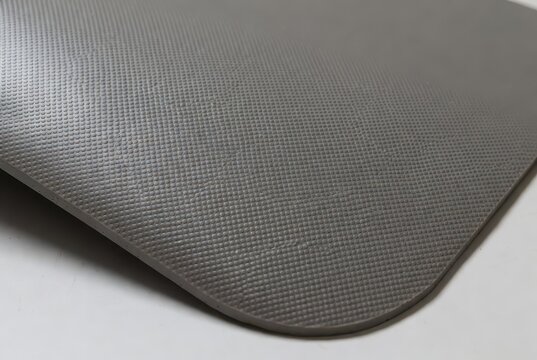 Close-up of a textured gray yoga mat with a dimpled surface on a white background