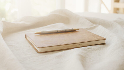 Fototapeta premium Minimalist Leather Notebook and Pen on White Fabric for Note Taking and Planning