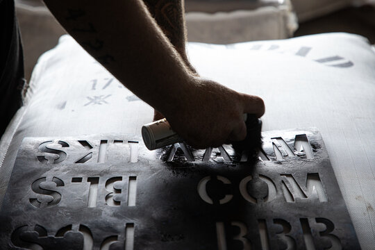 Applying a stencil to a bale of wool