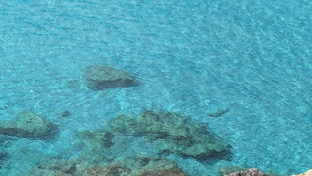 Blue sea water with small rocks in the foreground on Comino island, Malta
