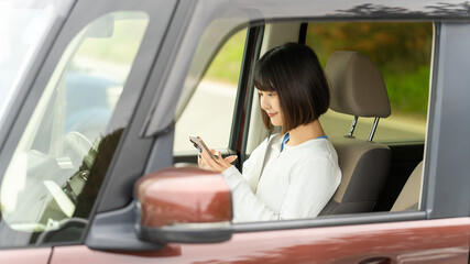 停車中にスマートフォンを操作する女性・ビジネスウーマンのライフスタイルイメージ, Businesswoman Using Smartphone While Parked in Car © Trickster*