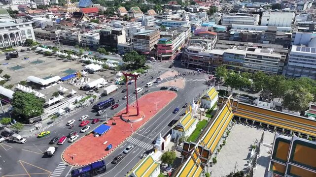The red GiantSwing and wat suthat thepwararam temple appear within active city streets, historic architecture and movement around.