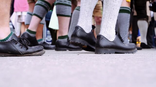 M&auml;nner in Tracht mit Lederhose und Haferlschuhen laufen auf dem Oktoberfest