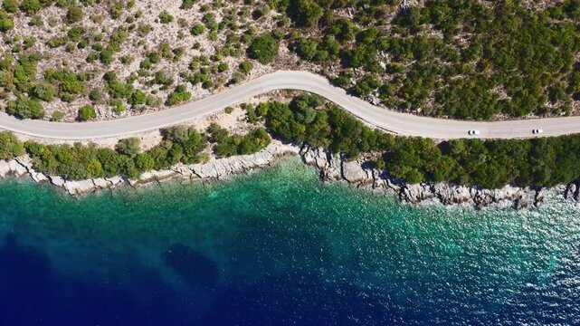 4K Drone footage of three cars moving by the sea curved road near a tranquille waves on the Greek coast on Cephalonia island. Transportation, nature concept.