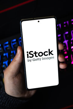 Punta Arenas, Chile &ndash; April 30, 2026: A person holding a smartphone displaying the iStock by Getty Images logo in front of a dark computer keyboard with glowing purple and blue LED lights