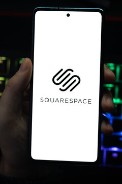 Punta Arenas, Chile &ndash; April 30, 2026: A person holding a smartphone displaying the Squarespace logo on its screen with a vibrant, colorfully backlit mechanical keyboard in the background