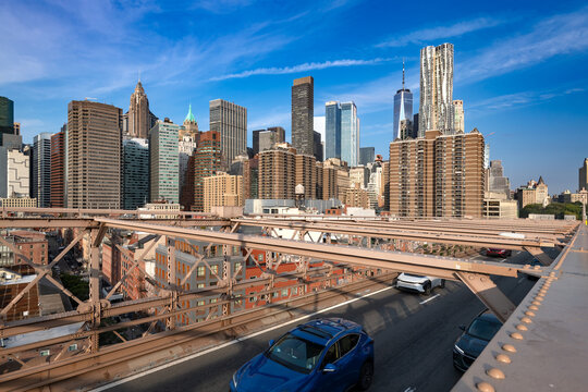 Vehicles drive across the steel structure of the Brooklyn Bridge with the dense skyline of Lower Manhattan in the background, New York.
