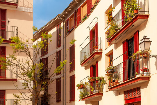 Red shutters and narrow balconies characterize the classic mediterranean architecture found in the historic streets of Palma de Mallorca, Spain.