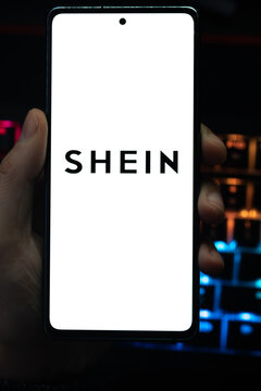 Punta Arenas, Chile &ndash; April 30, 2026: A person holding a smartphone displaying the SHEIN logo on its screen with a vibrant, colorfully backlit mechanical keyboard in the background