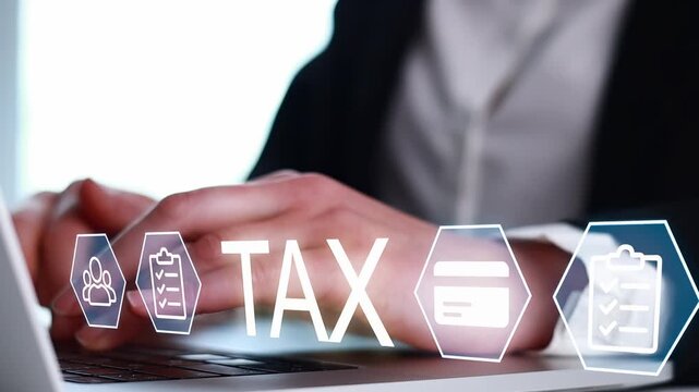 Tax preparation is taking place on a laptop with hands typing and various icons displayed around the screen in a business setting.