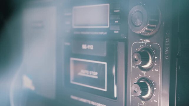 A close-up of a vintage black cassette recorder as cinematic smoke drifts past its tuning knobs. Concept of retro technology nostalgia, classic music broadcasting, and mystery.