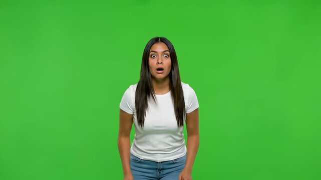 Surprised Woman Against Green: A portrait of a woman with an expression of shock and awe, eyes wide, mouth agape, posing in front of a chroma key green backdrop. The scene captures pure astonishment.