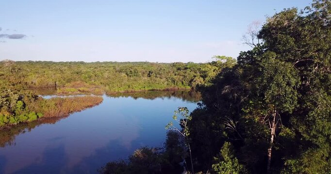 Aerial view of Amazon river at sunset flying over rainforest and water with Puente Nanay bridge near Iquitos Peru smooth drone shot 4K