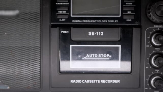 A close-up of a woman hand pushing a button to close the cassette deck on a vintage radio recorder. Concept of nostalgia, retro technology, 80s music, and vintage audio equipment.