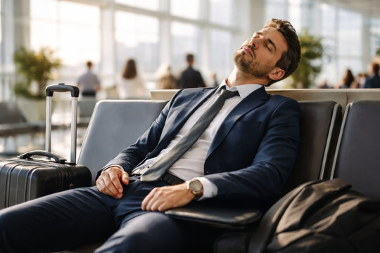 Businessman resting in airport lounge with suitcase beside him