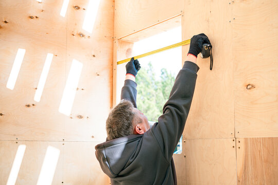 Professional unrecognizable constructor using ruler to measuring window frame