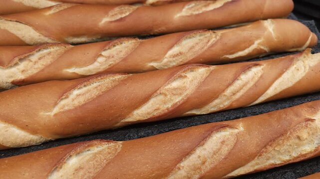 Close-up view of freshly baked baguettes with a golden crispy crust and traditional scoring. The warm tones and detailed texture highlight the artisanal quality of the bread