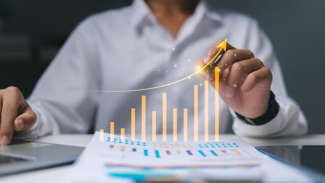 Financial success and investment profit with rising bar chart,Data visualization of exponential growth in modern business,Businessman drawing virtual increasing graph for business growth.