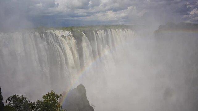 Powerful Victoria Falls on Zambezi River creating misty spray and rainbow on Zambia and Zimbabwe border in southern Africa, Mosi oa Tunya National Park landscape