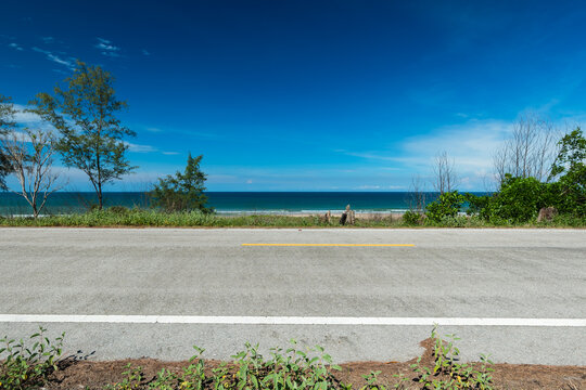 Side view of asphalt road with beach on sea and beautiful blue sky. Road background.