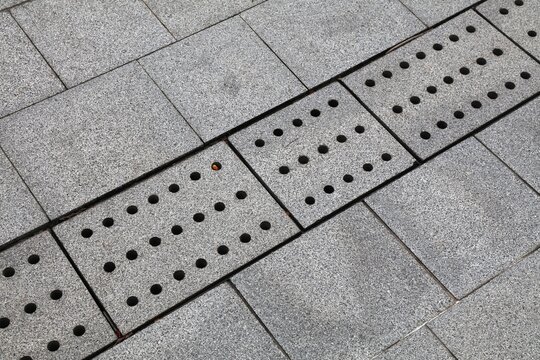 Granite drainage ditch grate. Stone rainwater gutter cover in pedestrian walkway in Singapore city. Urban infrastructure.