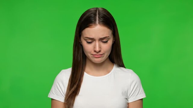 Melancholy Reflection: Portrait of a woman expressing deep sadness and reflection, conveying vulnerability and raw emotion, against a vivid green backdrop.