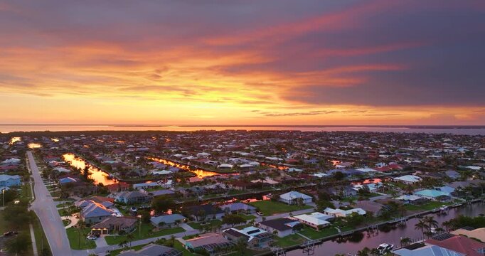 Sunset aerial view of Punta Gorda wealthy neighborhood. Expensive residential homes along canals reflect warm evening sky.