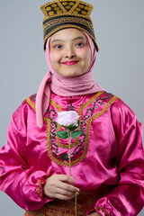 Fototapeta premium Smiling Young Indonesian Asian Girl Wearing Pink Hijab and Traditional Costume Holding a Rose Portrait