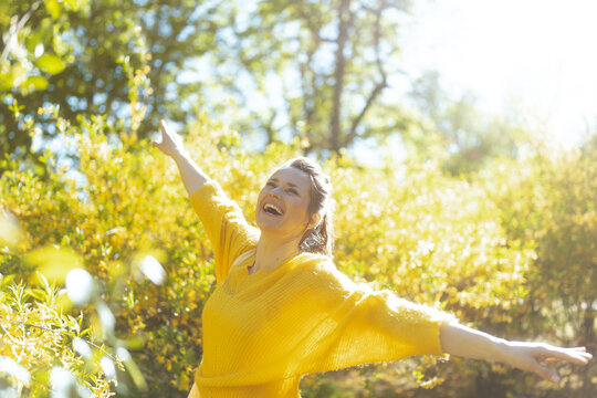 A woman basking in the glow of a sun-drenched spring day with arms outstretched. This image captures the essence of lifestyle freedom, mental wellbeing, and connection with nature.