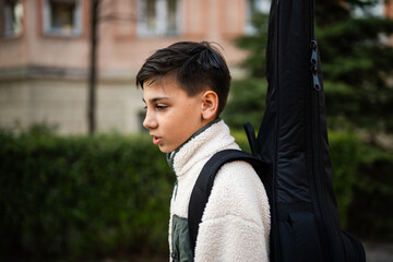 Boy walking carrying guitar case for music lesson © Zoran Jesic