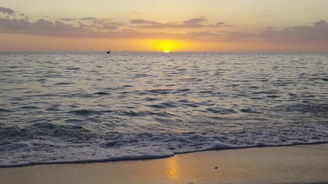 Vibrant sunset over ocean horizon with dramatic cloudscape. Warm sun rays illuminating water surface and creating breathtaking coastal environment.