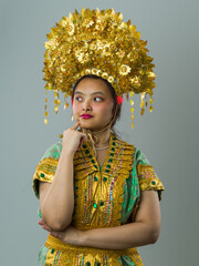 Fototapeta premium Portrait Of Young Indonesian Asian Woman Wearing Ornate Gold Headdress And Traditional Costume Expressing Thoughtful Confidence
