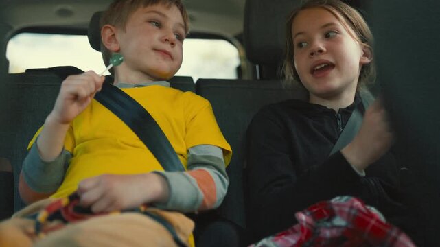 Children travel in a car while enjoying candy and having fun