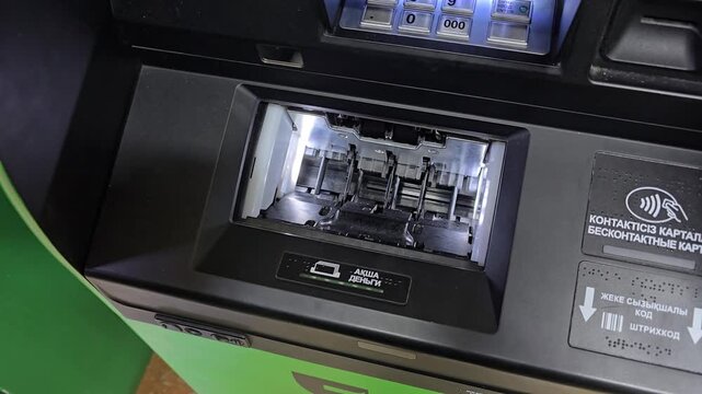 Depositing cash into an ATM (Kazakhstani tenge). A man places a stack of 10,000 and 20,000 tenge bills into the bill acceptor of a modern ATM. 