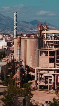 Abandoned industrial factory complex showing rusty silos, pipes, and smokestacks