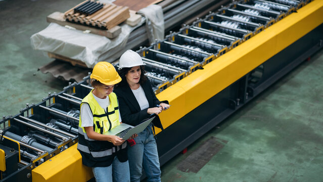 Team of Engineers and Technicians Measuring and Inspecting Metal Steel Sheets on Production Line Inside a Modern Industrial Manufacturing Facility.