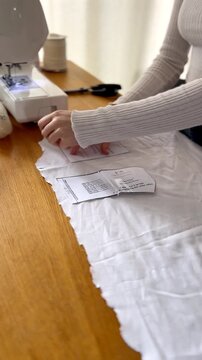 Woman Cutting Sewing Pattern on White Fabric at Home
