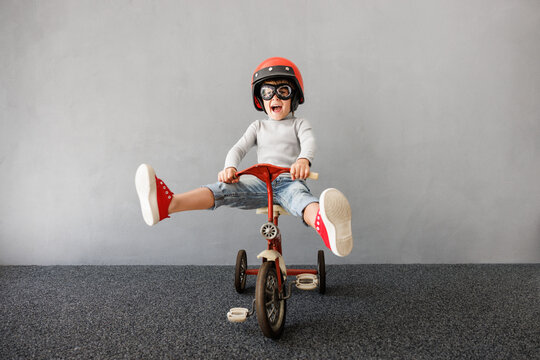 Happy child riding a bike. Funny kid pretend to be racer.. Little boy playing indoors
